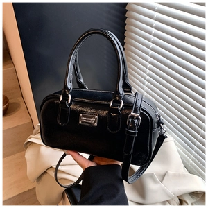 Close-up of a glossy black Boston bag featuring silver hardware and a sleek metal plaque