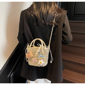 Detail of straw bucket bag with cute bear charm and woven strap on a female model