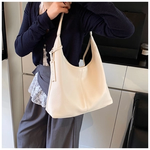 Detail of a large off-white lychee grain leather hobo bag worn as a shoulder bag