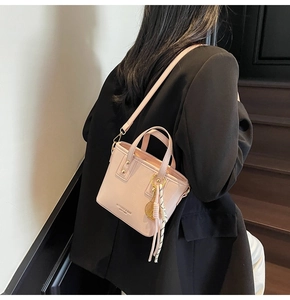 Pink lychee grain leather mini tote bag with tennis racket charm on a black blazer