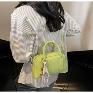 Detail of green leather pillow bag with colorful bead charm and adjustable strap
