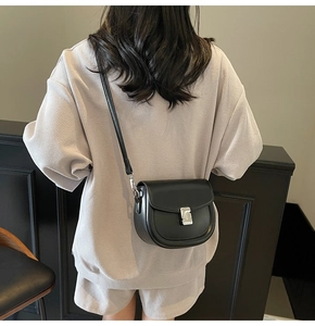 Model view of black leather saddle bag with silver clasp and slim shoulder strap