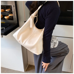Detail of off-white lychee grain leather tote bag with brand tag and spacious interior
