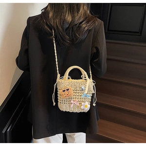 Detail of hand-woven beige bucket bag with plush bear, colorful bows and drawstring