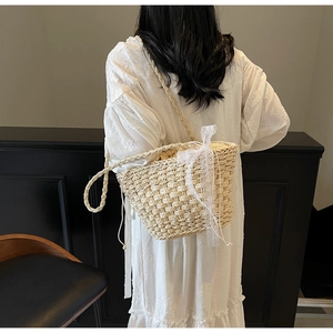Détail du sac bandoulière en paille avec nœud en dentelle blanche et cordon de serrage