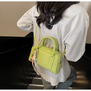 Detailed close-up of a green Boston handbag with lychee pattern leather and silk scarf