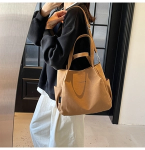 Dettaglio della borsa tote in tela con tasca laterale, logo e tracolla regolabile