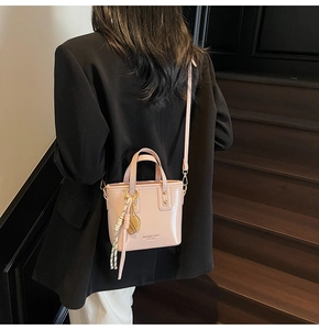 Pink patent leather bucket bag featuring gold leaf charm and embossed logo detail