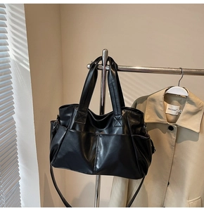 Detail view of black PU leather tote with front pockets and adjustable shoulder strap