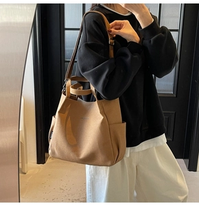 Dettaglio della borsa tote in tela kaki con tracolla e tasche laterali per pendolari