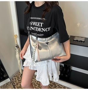 Detail of silver metallic bucket bag featuring triangular logo and braided rope pendant