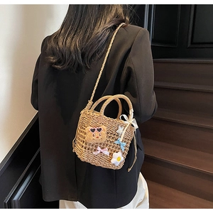 Detail of woven straw bucket bag featuring cute bear charms and colorful accessories