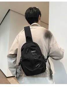 Detail of black crossbody chest bag with large logo and checkered bear charm on a male model