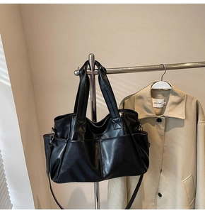 Detail of black PU leather tote bag with multiple pockets and adjustable shoulder strap