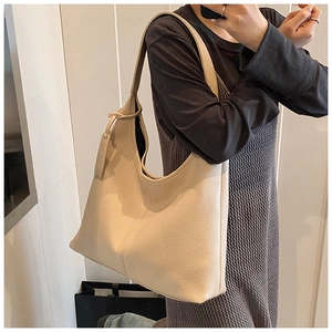 Detail view of beige lychee textured leather tote bag on model for commuter style