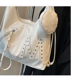 Close-up of a cream hobo tote bag featuring a studded silver M logo and mini round coin pouch