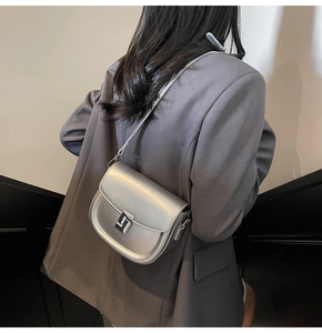 Silver metallic saddle bag shown from side back view on a model in dark blazer