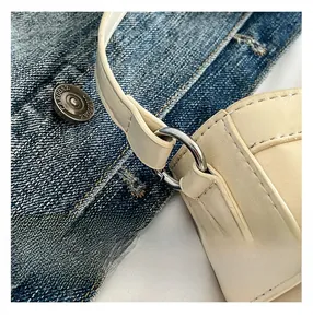 Détail de la bandoulière en cuir beige avec anneaux en métal argenté et coutures