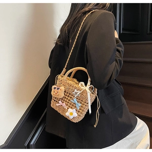 Close-up of woven straw bucket bag featuring a plush bear charm and decorative bow details