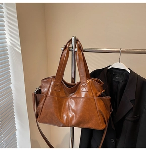 Macro detail of large brown vintage leather tote bag with wide handles and side pockets