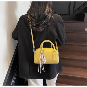 Chic yellow boston bag with lychee texture held by a model on wooden stairs