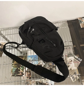 Detail of black sporty chest bag featuring glossy embossed lettering and padded strap