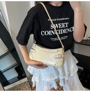 Détail du sac à bandoulière en cuir verni beige avec rivets argentés et style Y2K