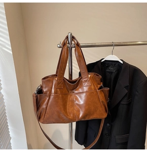 Detail of vintage brown leather tote bag with side pockets and removable shoulder strap