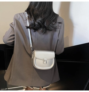 Close-up of a silver metallic saddle bag worn over a dark grey blazer with metal buckle
