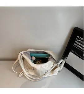 Top view of spacious cream leather tote bag interior with metal studs, books and perfume