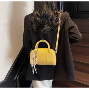 Detail of yellow boston bag with pebble grain leather texture and beaded strap charms