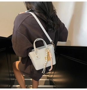 Detail of light gray mini tote bag with gold tennis racket charm and thin strap