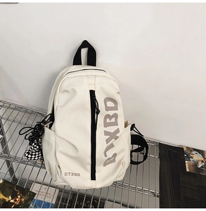 Close-up of cream crossbody bag with black straps and a checkerboard charm detail