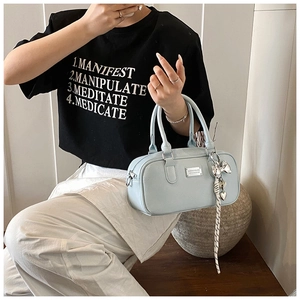Close-up of light blue Boston bag with litchi texture, metal heart charm and plaid ribbon
