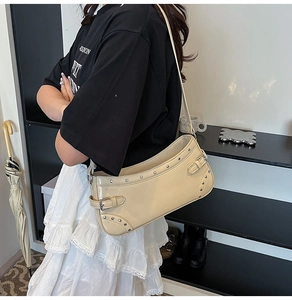 Détail du sac à bandoulière crème avec rivets argentés et finition en cuir verni brillant