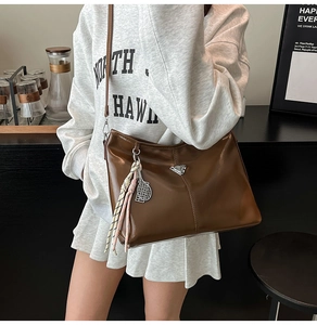 Close-up of brown soft leather tote bag featuring a silver triangle metal detail and tennis charm