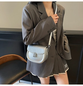 Detail view of silver saddle bag with metallic finish and square rotating metal clasp