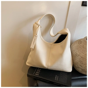 Detail shot of cream lychee texture leather tote bag on art book in aesthetic setting