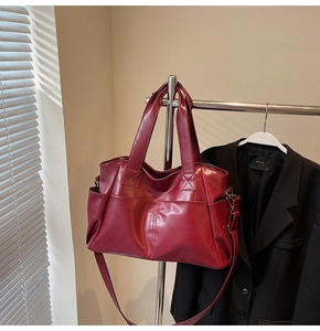 Detail view of burgundy leather tote bag featuring side pockets and elegant stitching