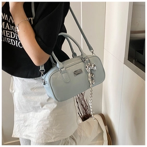 Light blue Boston bag styled with silver bow pendant and adjustable strap on model