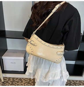 Gros plan du sac porté épaule crème en similicuir brillant avec rivets argentés