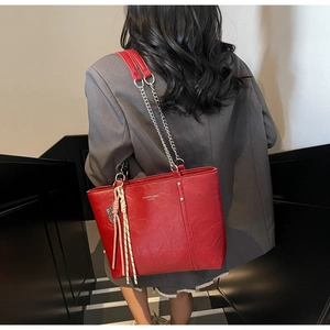 Detail of red leather tote bag with gold logo lettering and woven rope charm