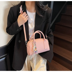 Pink Boston bag with lychee texture and colorful bead charm worn by a model in black