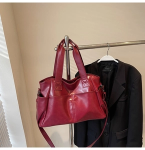 Detail of burgundy PU leather tote bag with functional pockets and shoulder strap