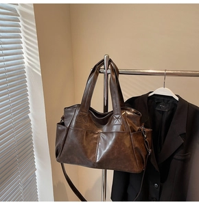 Detail view of large dark brown tote bag with side pockets and glossy faux leather texture