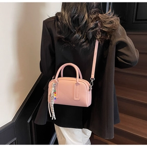 Pink lychee texture shoulder bag with decorative colorful bead and rope charm detail
