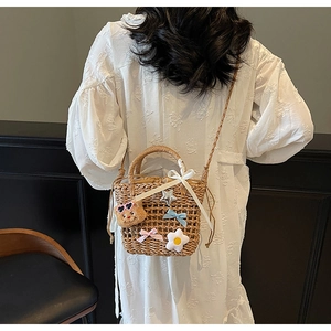 Close-up of woven straw bucket bag with cute bear charm and drawstring lining detail