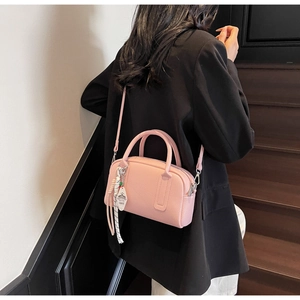 Pink lychee grain leather crossbody bag shown on black suit with chic fringe pendant