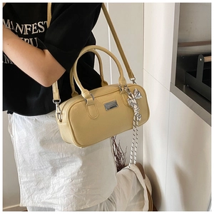 Fashionable pale yellow Boston bag with glossy finish shown on model in urban style