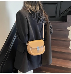 Detail view of a camel saddle crossbody bag with silver hardware on a black blazer